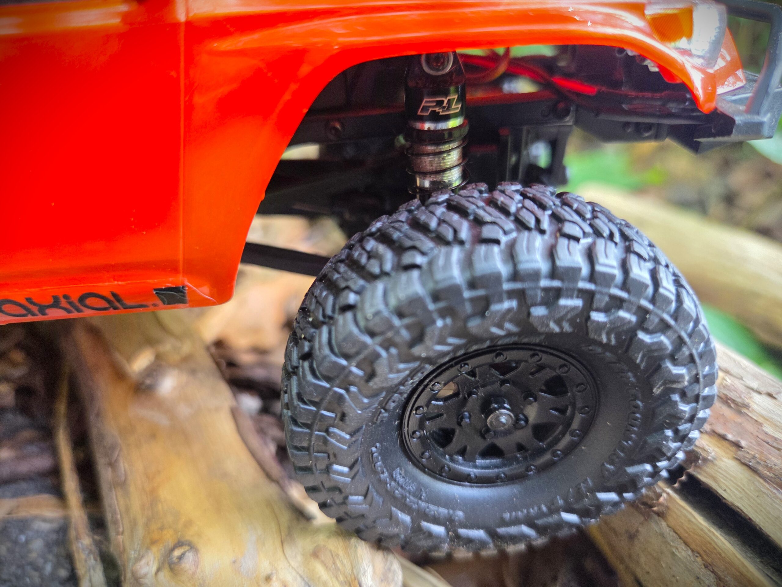 Close-up of Pro-Line oil-filled shock absorber and Toyo Open Country tire on orange Axial SCX24 Toyota 4Runner